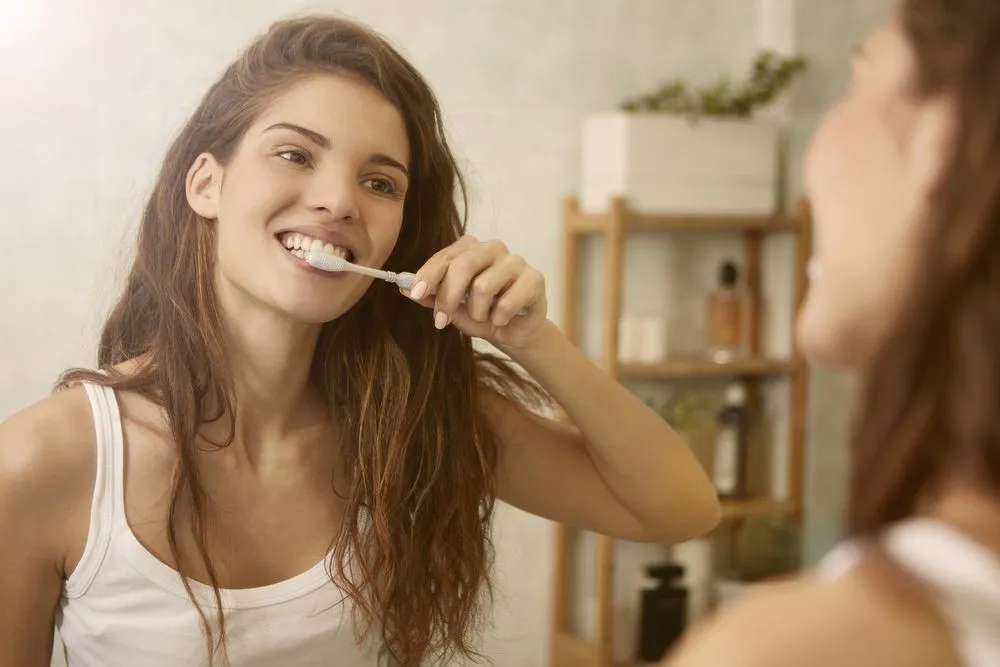 Woman brushing her teeth at her home.