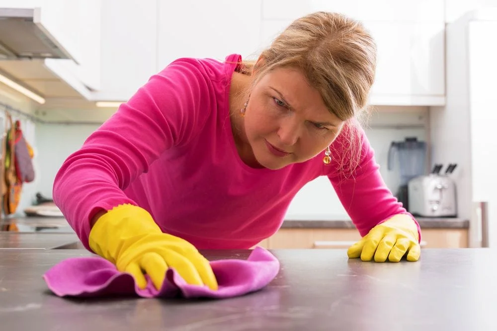 Woman wearing rubber gloves and scrubbing a counter top