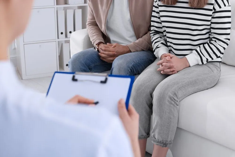 Couple talking with doctor holding a clipboard