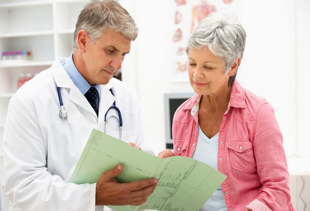 woman with chiropractor looking at her file after getting chiropractic treatment for her condition