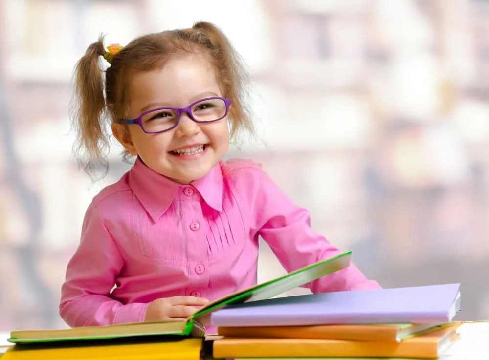Little girl having fun reading with her new glasses.