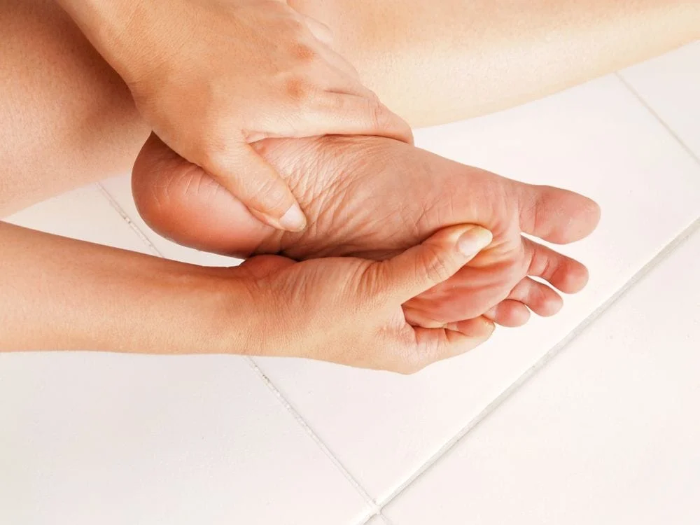 person with plantar fasciitis holding foot in pain