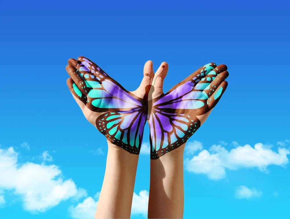 Hands uplifted with a multi colored butterfly