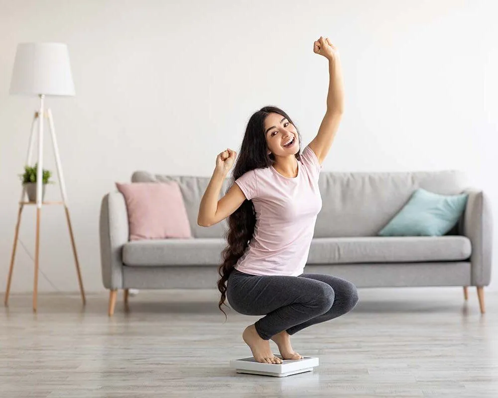 Woman Smiling while crouching on a scale