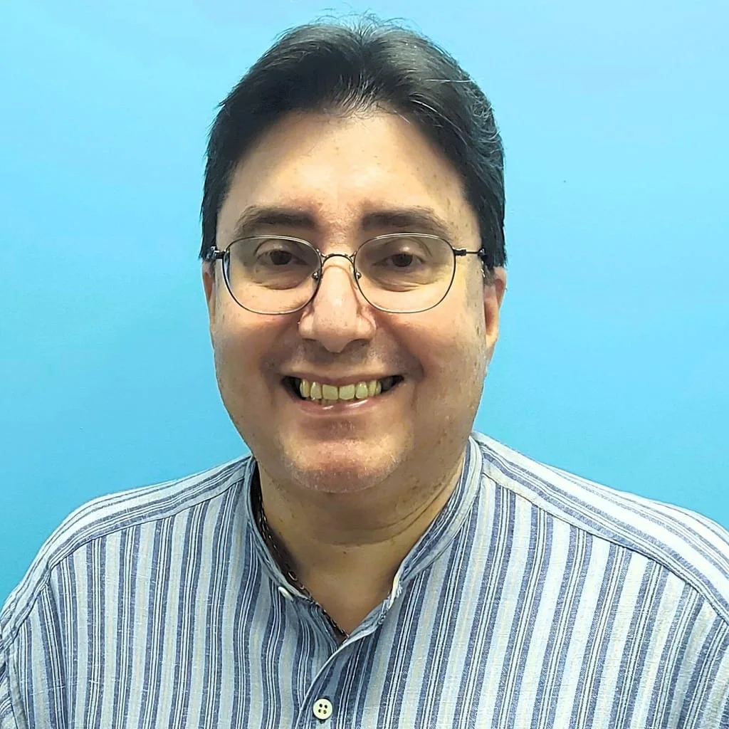 Dr. Hector De Leon smiling in front of blue background