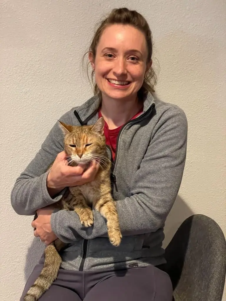 A woman smiling while holding a cat