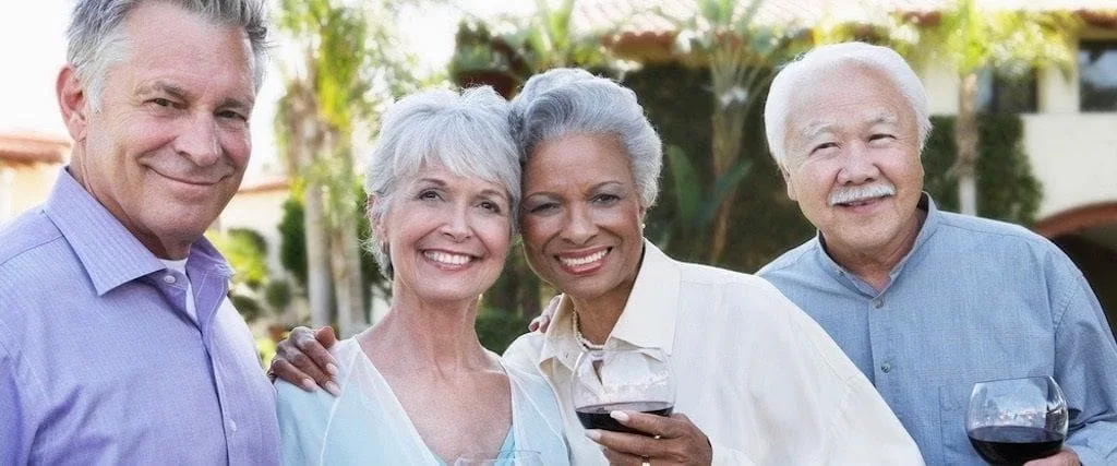 two elderly couples smiling holding glasses of wine outside, dental implant restoration Millbrae, CA dentist
