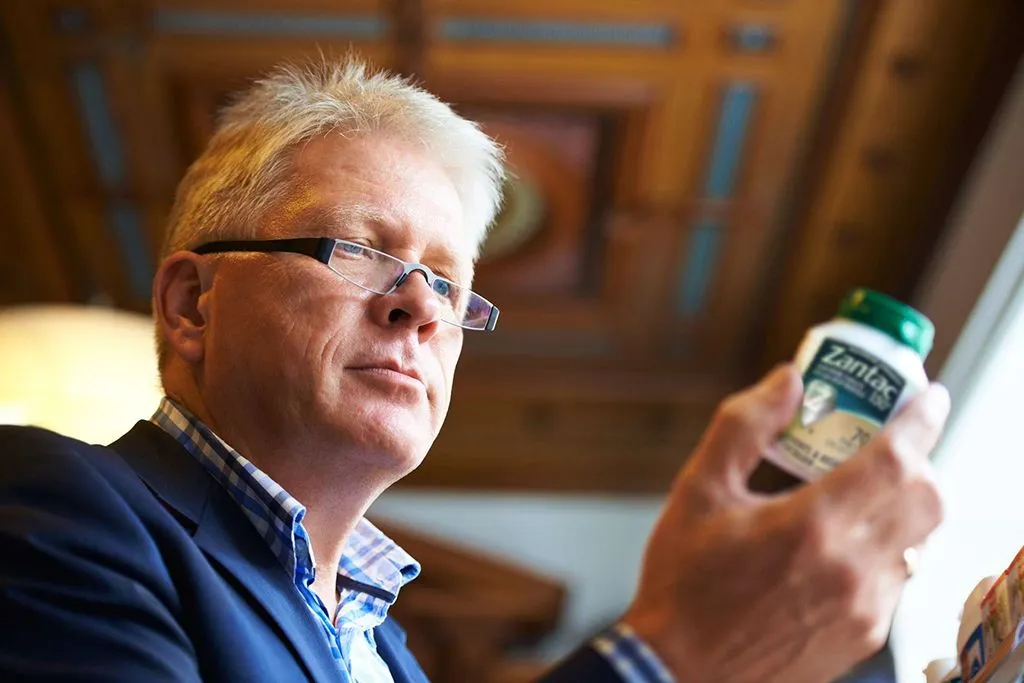 A man looking at a Zantac bottle