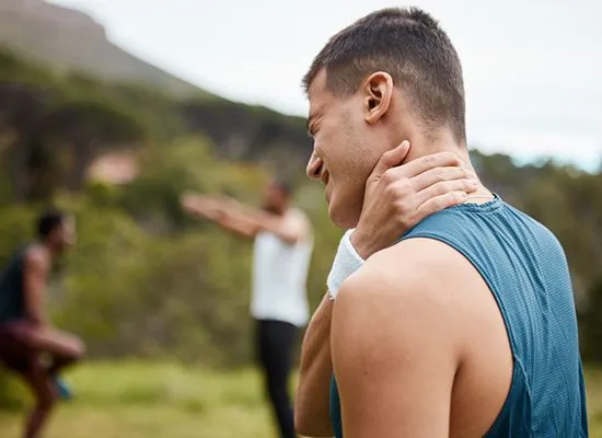 Man holding neck in pain outdoors