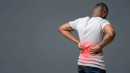 A man putting both hands on his back in pain