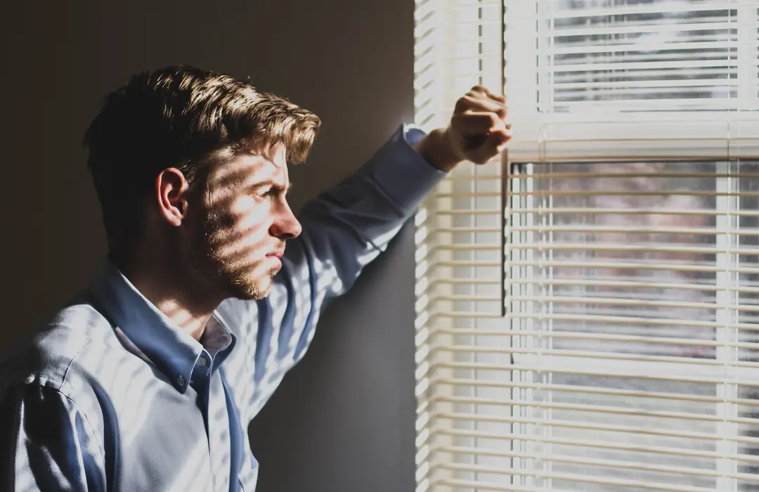 man looking out window