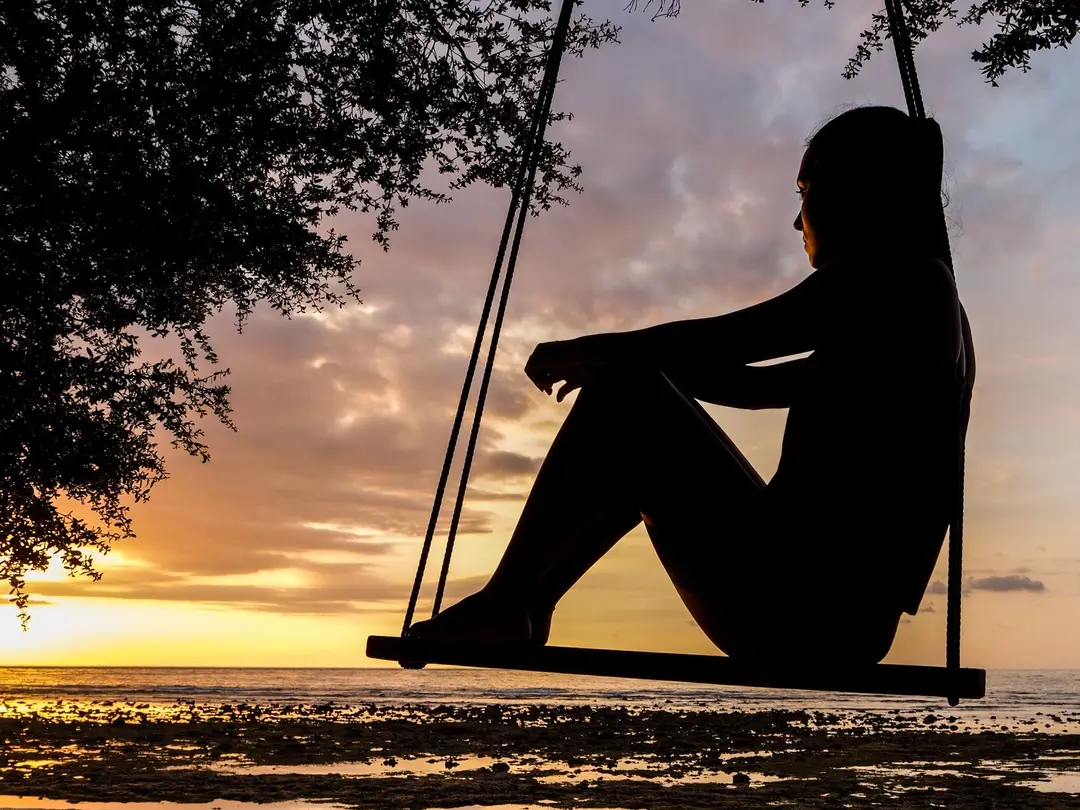 person on swing at sunset