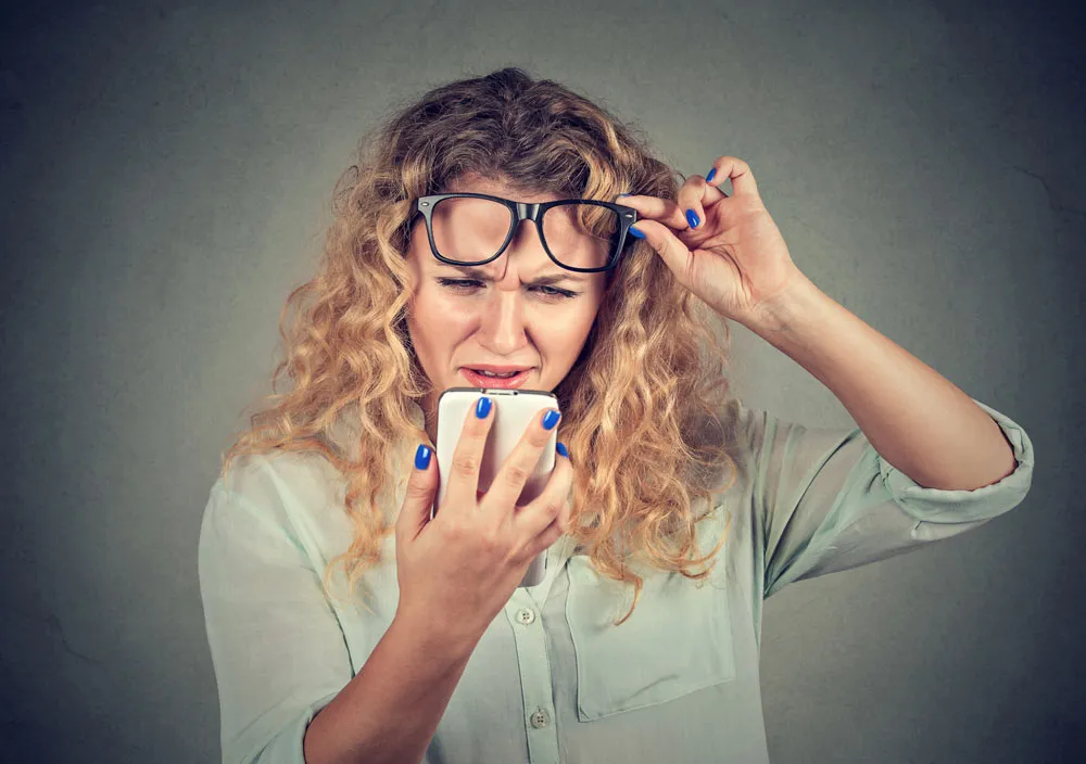 woman reading her phone with difficulty