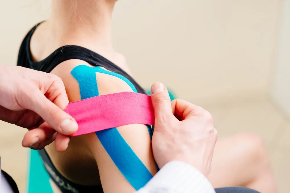 woman having Kinesio tape applied to her shoulder