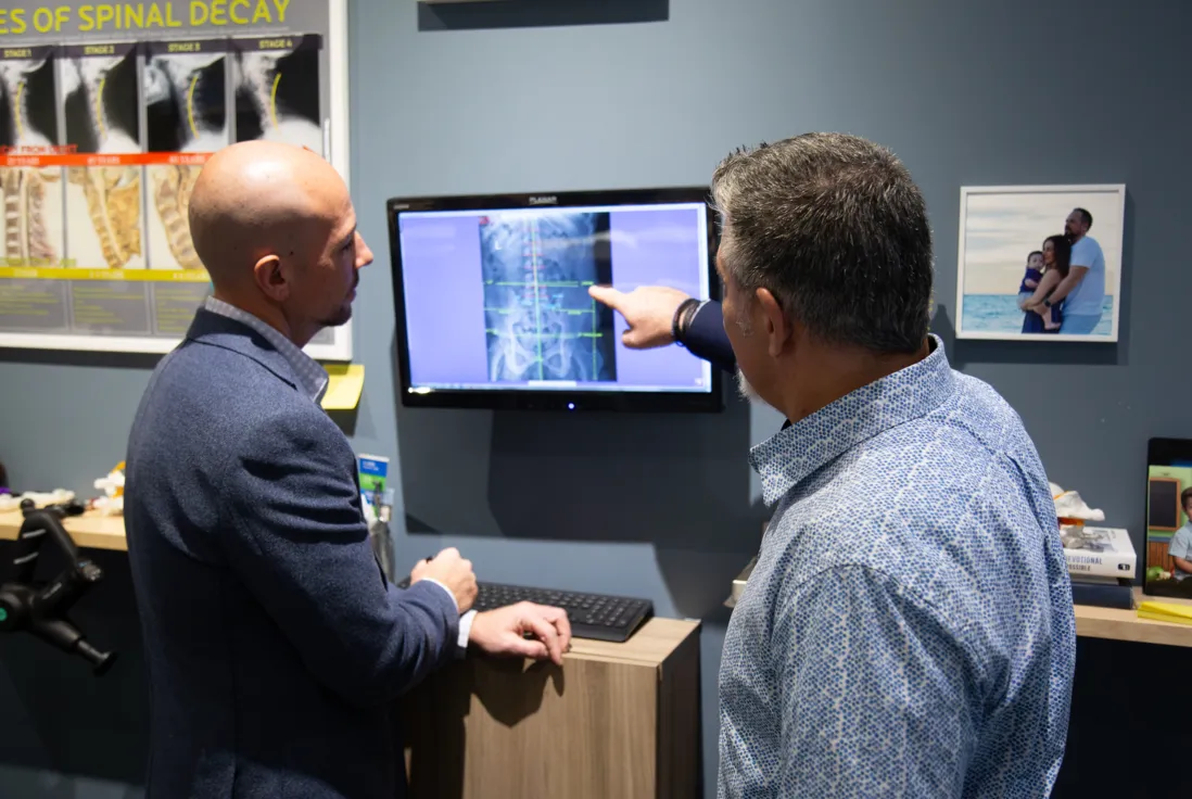 Chiropractor reviewing digital X-rays with a patient to explain spinal alignment and create a personalized care plan