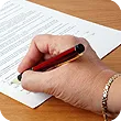 A person signs consent forms holding a red pen