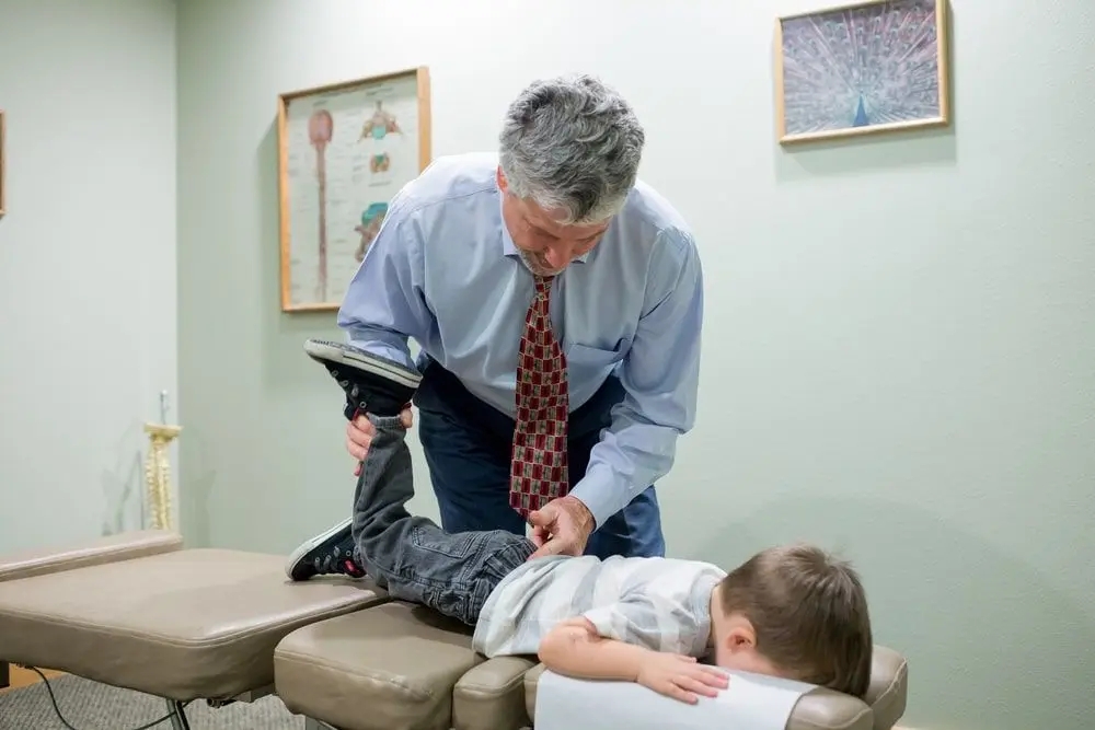 A doctor lifing a kids leg