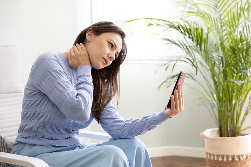 woman holding a phone and her sore neck