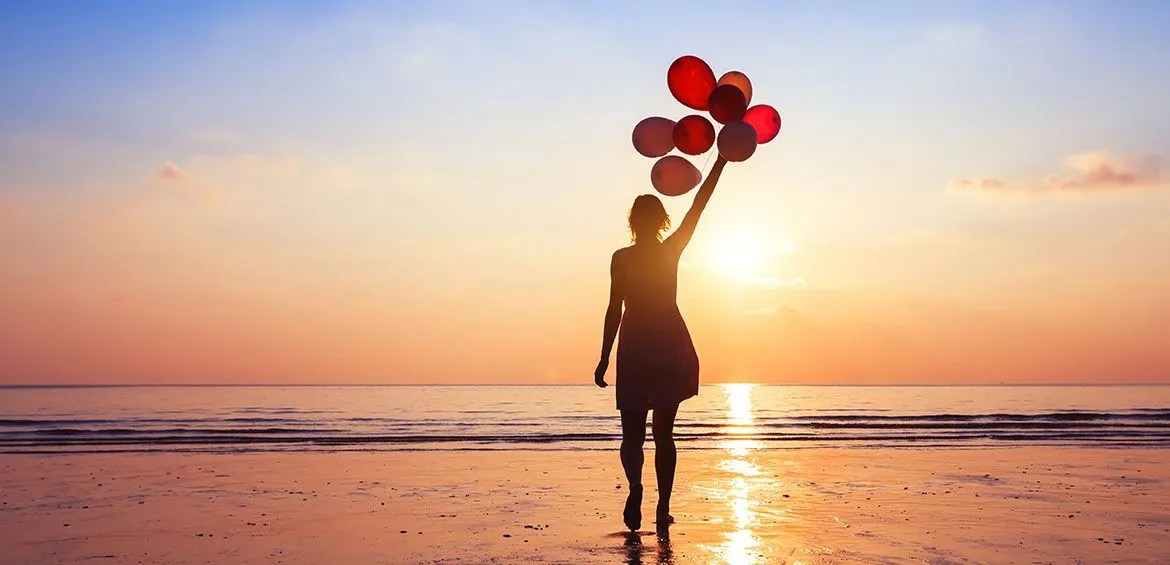 Girl holding bunch of balloons