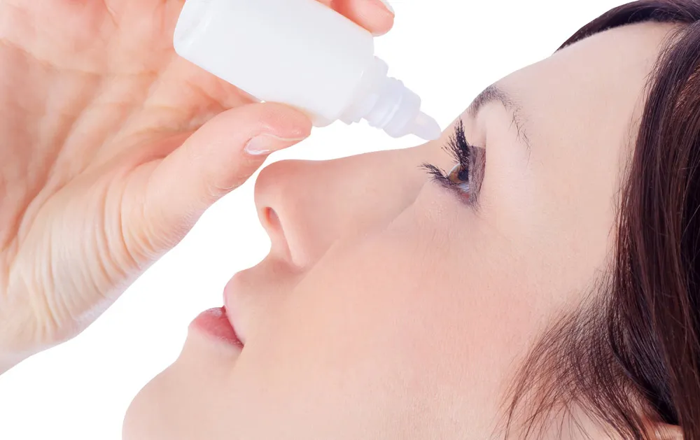 A woman putting eye drop