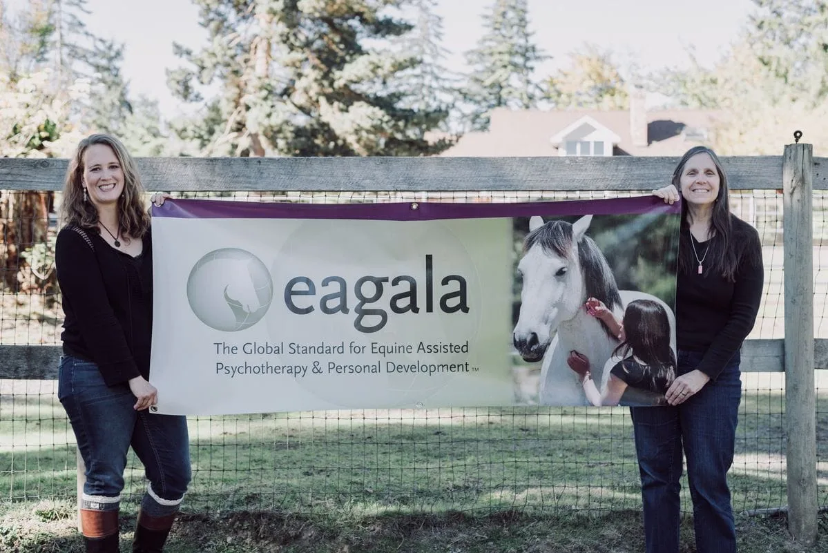 SHOLEH LULHAM and Peg Foley standing with one large and one small horse