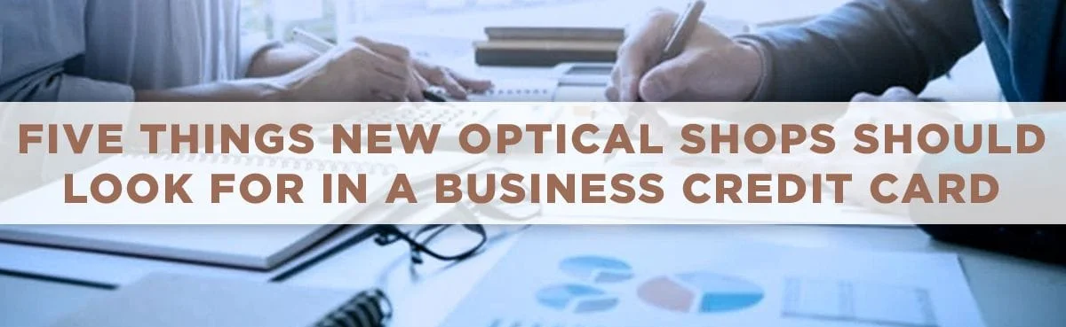 Five Things New Optical Shops Should Look For in a Business Credit Card (hands of man and woman at desk with charts, calculator, glasses)