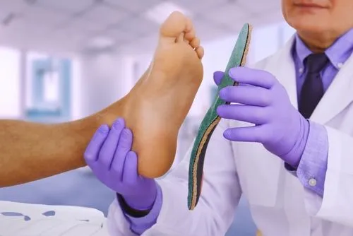 Doctor holding a patient’s foot while fitting custom orthotics to improve alignment and relieve foot pain.