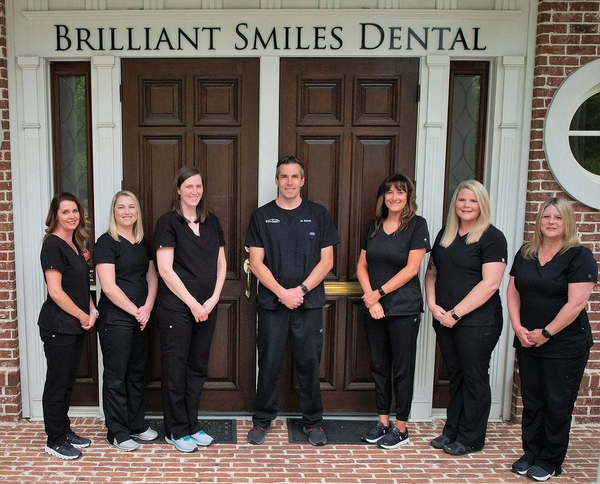 Dr James Reid Roberts & staff standing outside doors of Brilliant Smiles Dental, Peachtree City GA