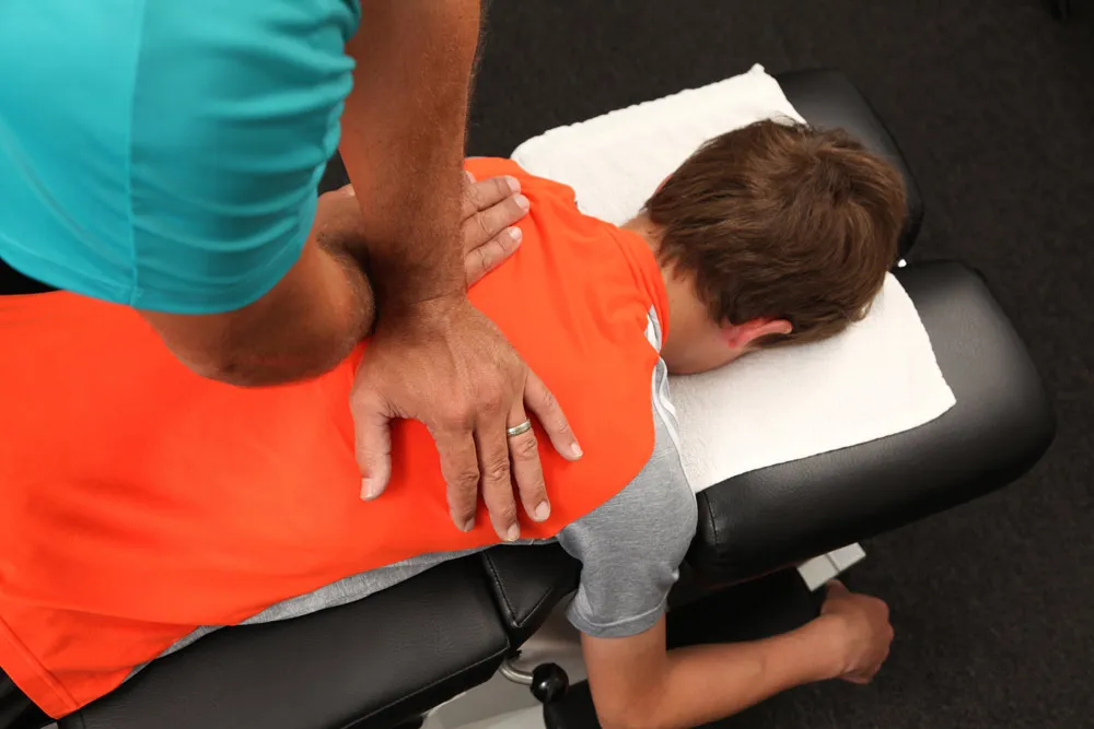 Chiropractor's hands adjusting a patient's back