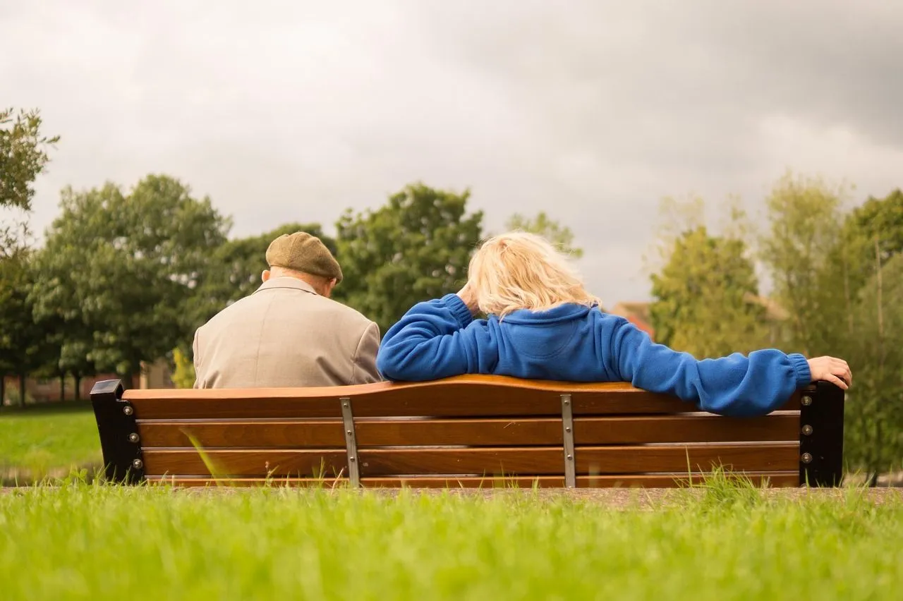 older couple sitting on a park bench together