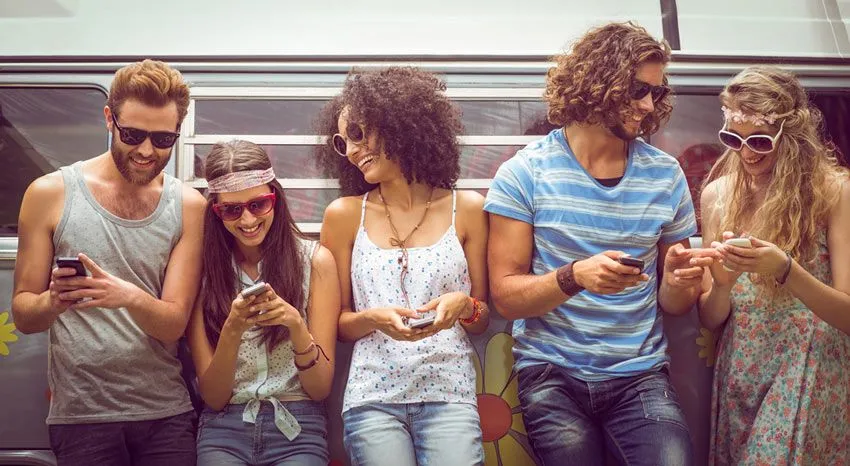 a group of people looking at their phones with sunglasses on