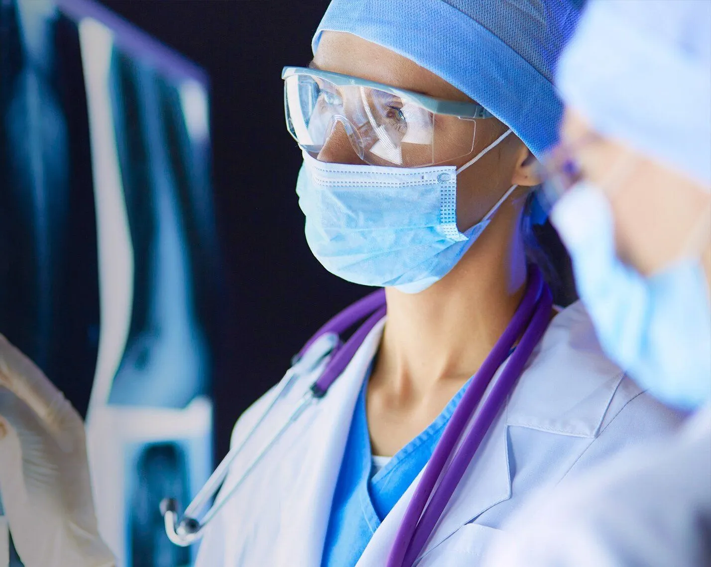 Medical providers with masks and protective glasses viewing x-rays