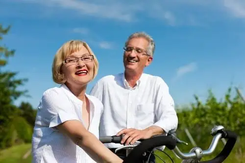 Elderly copule riding bikes outside.