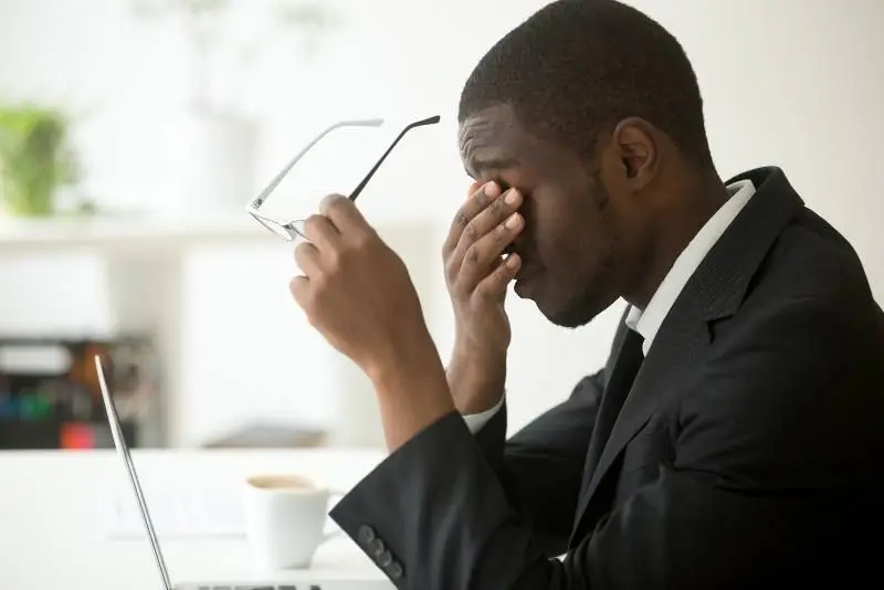 Tired man in glasses rubbing nose bridge