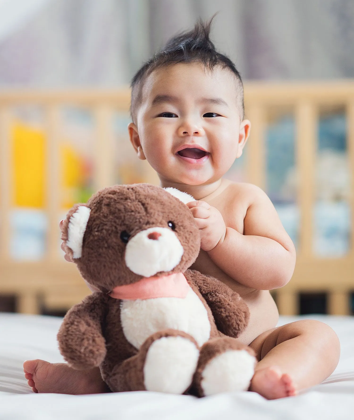 Little baby boy holding brown teddy bear
