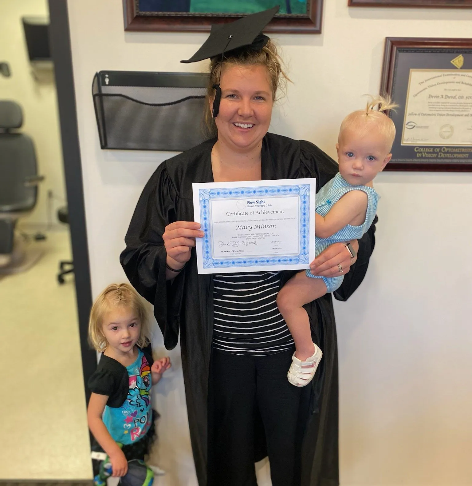 woman holding a certificate of graduation and her kids