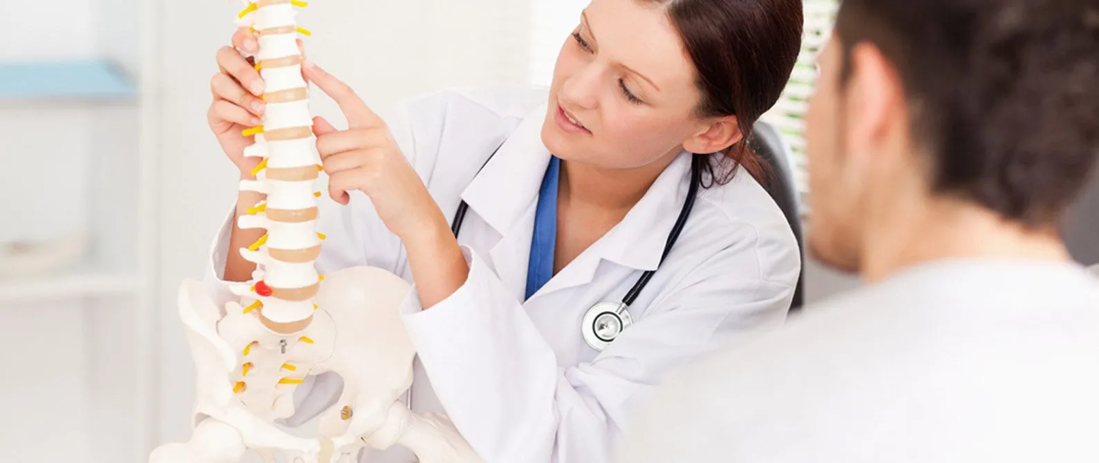 patient with chiropractor holding a model of a spine to show where a spinal injury is