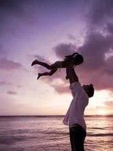 father lifting daughter up towards the sky