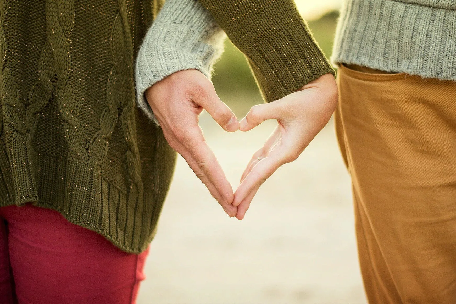 Two people with linked hands forming a heart