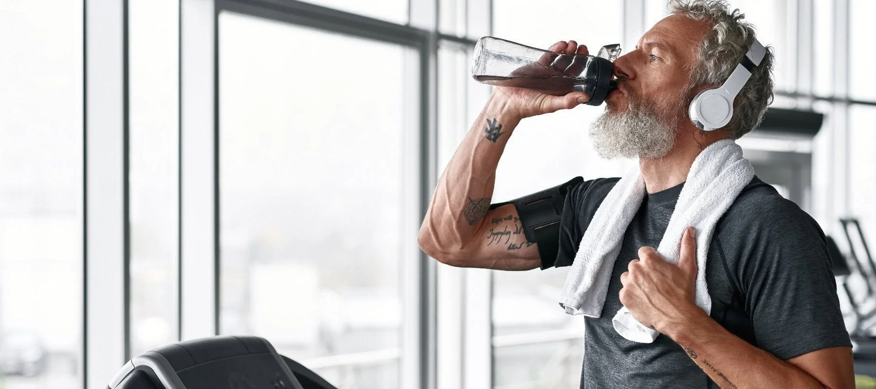 Fit Elderly Man on Treadmill Drinking Water Bottle