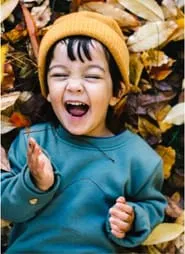 boy laughing in leaves