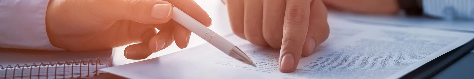 Hands holding a pen reviewing contract law details