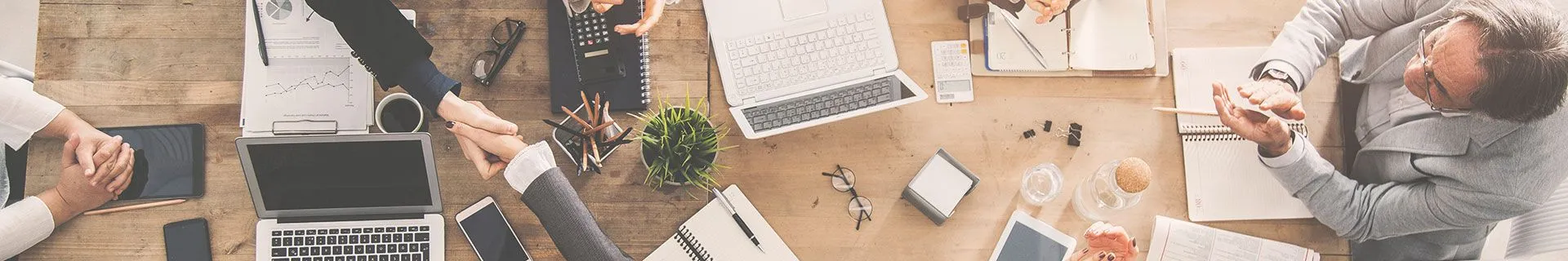Business law attorneys collaborating at a desk with laptops, contracts, and office supplies