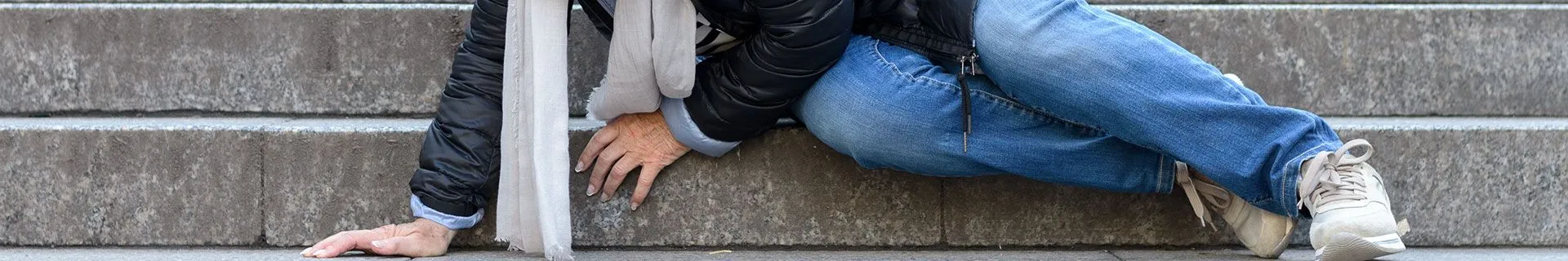 Person fallen at the bottom of stone stairs illustrating slip and fall injury claim