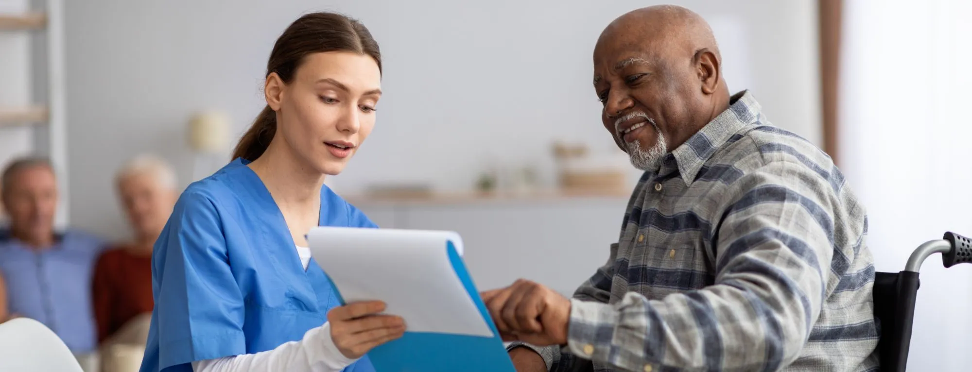 Healthcare provider showing older man in wheelchair a clipboard