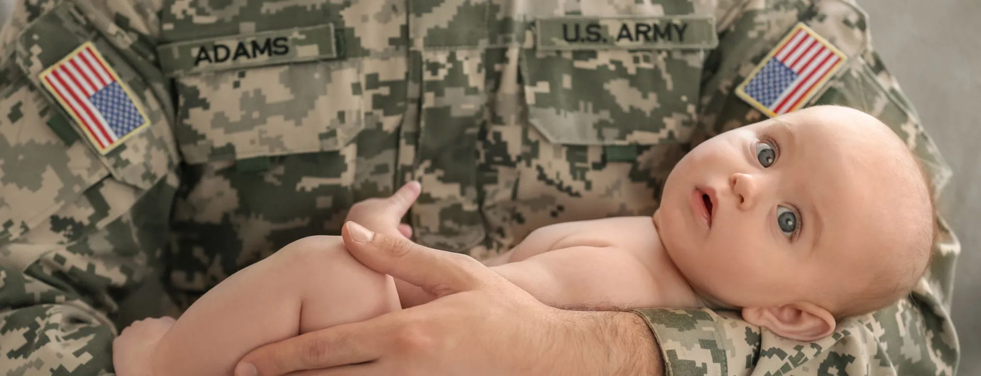 Military Man with the name "Adams" holding infant