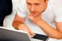 man laying in bed on computer