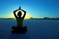 woman sitting in a yoga pose at sunrise