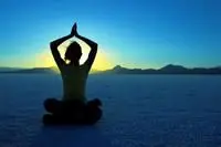 woman sitting in a yoga pose at sunrise