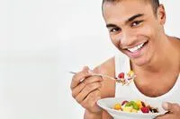 man smiling and eating salad